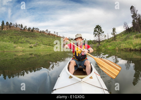 Senior sportliche Paddler in einem überdachten Expedition Kanu an einem See mit grüner vegetation Stockfoto