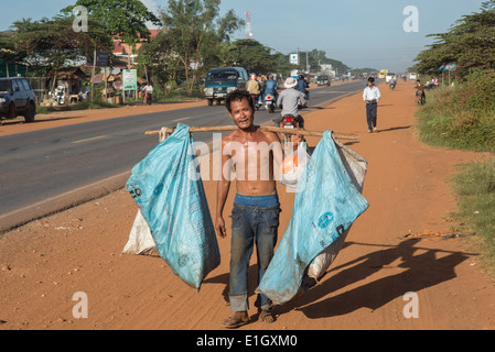 Mann sammelt Müll, Menschen pendeln, auf Fahrrädern auf einer staubigen Straße, in Kambodscha, LKW, Stockfoto