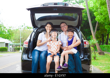 glückliche Familie sitzt im Auto und ihr Haus hinter Stockfoto