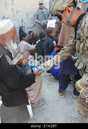 US Army Spc. Angel Mena gibt afghanischen Waise ein Spielzeugauto während einer Operation Outreach Besuch in einem Flüchtlingslager in Kabul, Afghanistan Stockfoto