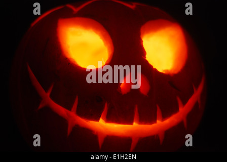 Ein furchterregend gesichter, geschnitzter Halloween-Kürbis, der von innen angezündet wurde Ein schwarzer Hintergrund Stockfoto