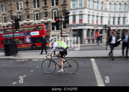 Mann trägt shorts, Helm und i-viz gelb Rucksack reitet seinen Rennrad-Straße entlang einer BusyLondon Straße. Stockfoto