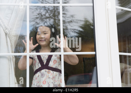 Junges Mädchen mit Blick vom Wohnzimmer Fenster Stockfoto