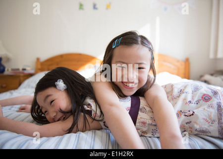 Zwei junge Freundinnen auf Bett liegend Stockfoto