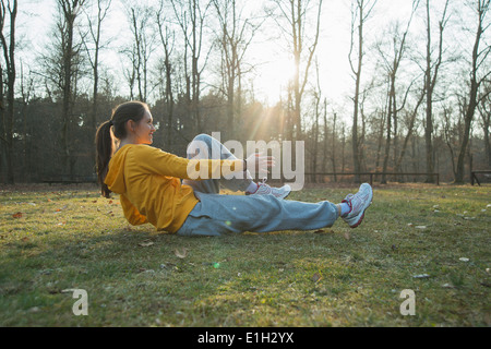 Junge weibliche Läufer Aufwärmen Sit-Ups zu tun Stockfoto