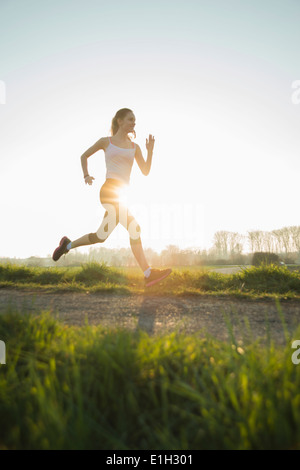 Junge weibliche Läufer auf sonnigen Feldweg Stockfoto