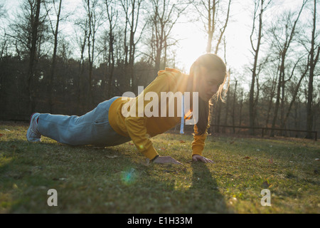 Junge weibliche Läufer Aufwärmen Presse Ups zu tun Stockfoto
