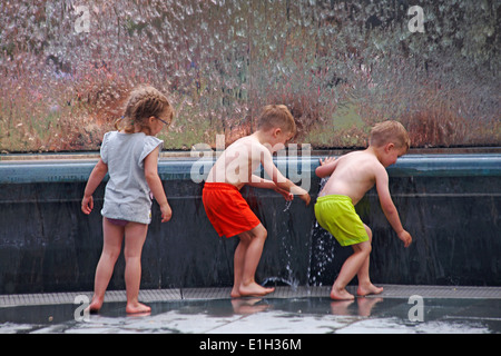 genießen das Wasser - Kinder spielen im Wasserbrunnen im Millenium Square, Harbourside, Bristol im Mai Stockfoto