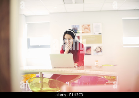 Junge Frau mit Kopfhörern mit laptop Stockfoto