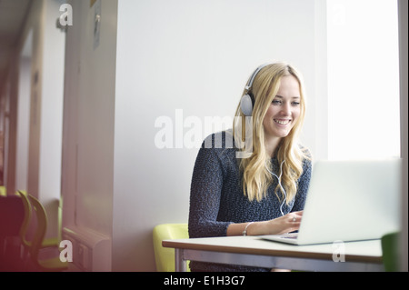 Junge Frau mit Kopfhörern mit laptop Stockfoto