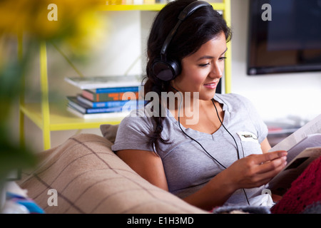 Junge Frau, lesen und Musik hören Stockfoto