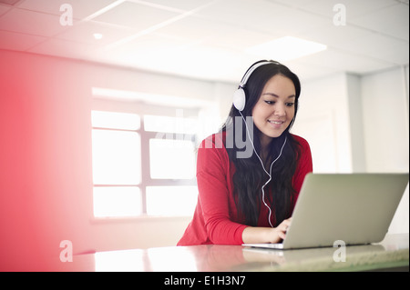 Junge Frau mit Kopfhörern mit laptop Stockfoto