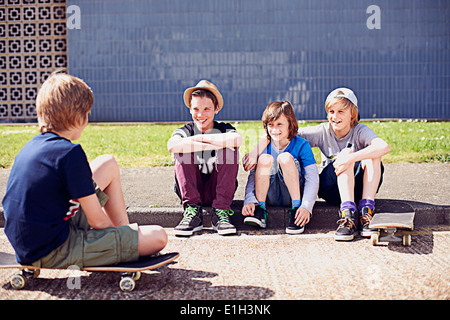 Jungen sitzen auf Asphalt mit skateboards Stockfoto