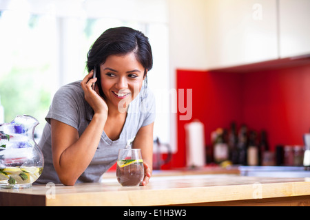 Junge Frau mit Handy in Küche Stockfoto