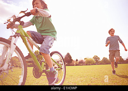 Jungen laufen und Radfahren auf Spielfeld Stockfoto