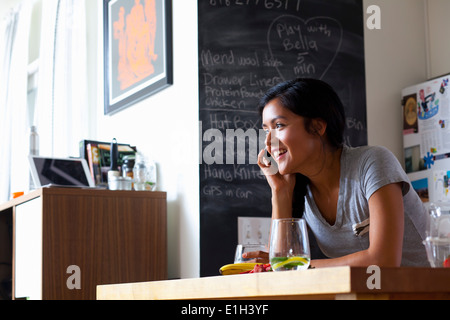 Junge Frau mit Handy in Küche Stockfoto