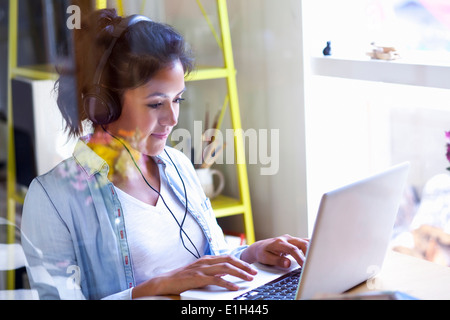 Junge Frau mit Kopfhörern mit laptop Stockfoto