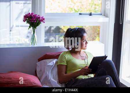 Junge Frau mit digitalen Tablet auf dem Bett Stockfoto