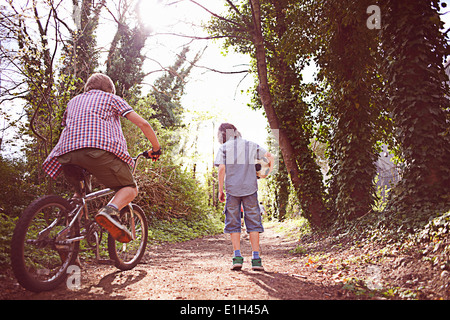 Junge auf Fahrrad mit Freund auf Waldweg Stockfoto