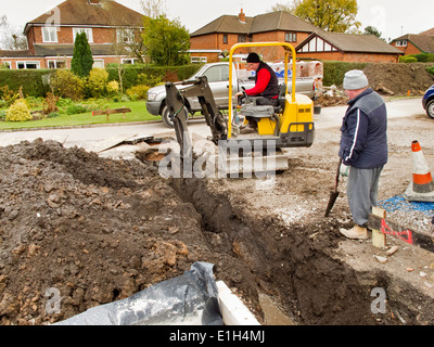 selbst Hausbau, Männer Ausheben von Gräben für Abflüsse mit Minibagger Bagger Maschine Stockfoto