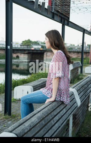 Junge Frau sitzt auf der Bank Stockfoto