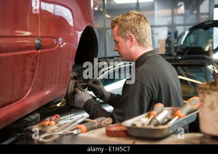 Ein Mechaniker in einer Garage ist die Überprüfung und Reparatur der Bremsen eines gehobenen Autos. Stockfoto
