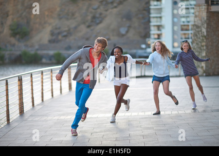 Vier junge Erwachsene Freunde laufen und Hand in Hand Stockfoto