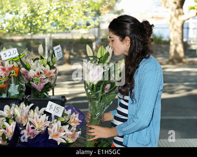 Junge Frau riechen Schnittblumen auf Straße Stockfoto