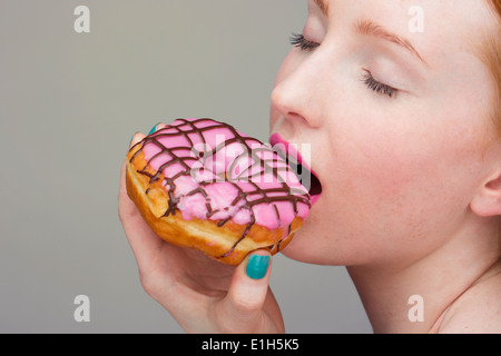 Junge Frau beißen donut Stockfoto
