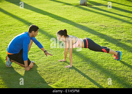 Personal Trainer mit Frau Plank Übung Stockfoto