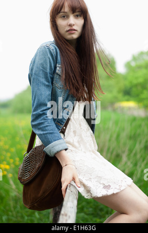 Portrait von junge Frau sitzt auf dem Zaun im Bereich Stockfoto