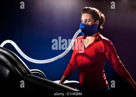 Mitte Erwachsene Frau mit Gesichtsmaske auf Fitness-Studio-Laufband in Höhe Mitte Stockfoto