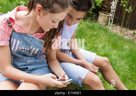 Teenager-paar Blick auf Smartphone im Garten Stockfoto