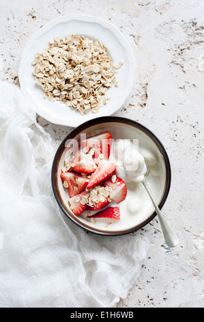 Stillleben mit Schalen Joghurt mit in Scheiben geschnittenen Erdbeeren und Hafer Stockfoto