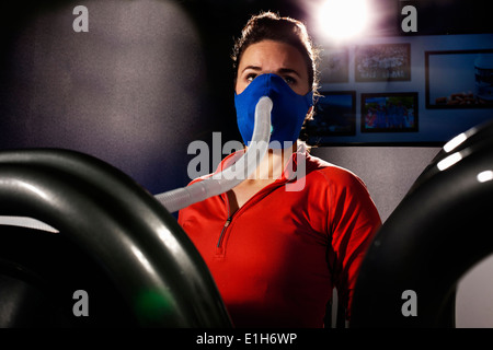 Mitte Erwachsenfrau mit Gesichtsmaske auf Fitness-Studio-Laufband in Höhe Mitte Stockfoto