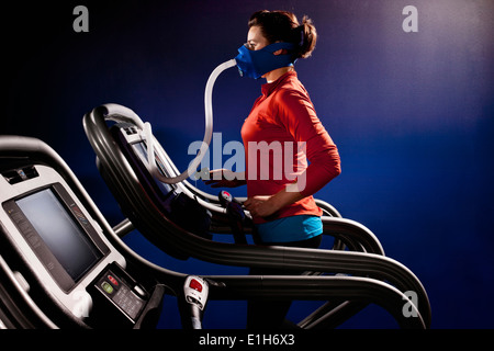Mitte Erwachsene Frau mit Gesichtsmaske auf Fitness Laufband in Höhe Mitte Stockfoto