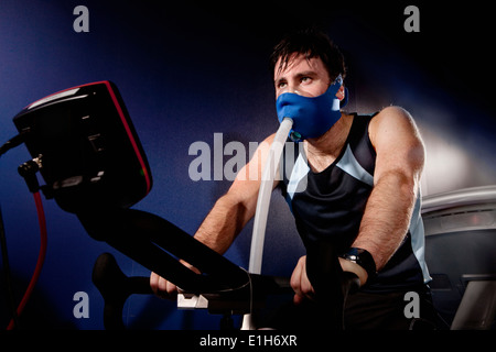 Mitte erwachsenen Mannes in Gesichtsmaske auf Gym Übung Zyklus in Höhe Mitte Stockfoto