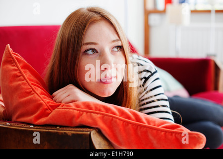 Junge Frau auf dem roten Sofa liegend Stockfoto