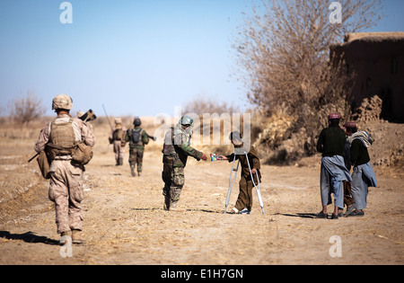 Afghan National Army Soldat Taza Khan übergibt einen Beutel mit Dörrfleisch ein Lokalmatador, verletzt durch eine improvisierte explosive Vorrichtung, whi Stockfoto