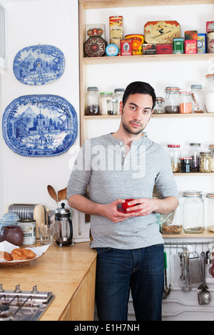 Mitte erwachsener Mann stehend in der Küche halten Kaffeetasse Stockfoto