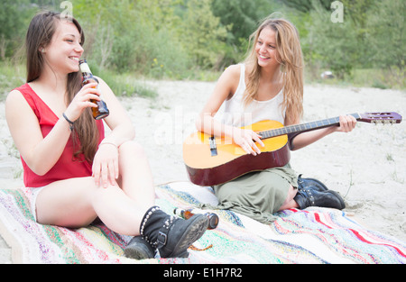 Freunde sitzen in Feld, Gitarre spielen Stockfoto