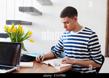 Junger Mann sitzt am Tisch, schreiben in notebook Stockfoto