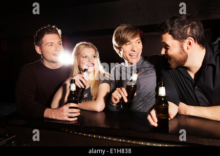 Vier Freunde trinken Flaschenbier in Nachtclub Stockfoto