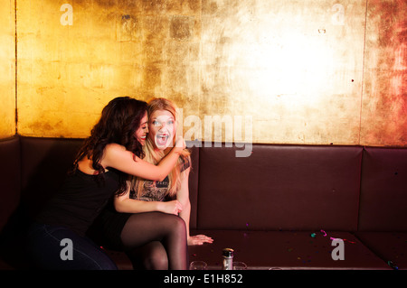Zwei Freundinnen, die mit einem Lachen in Nachtclub Stockfoto
