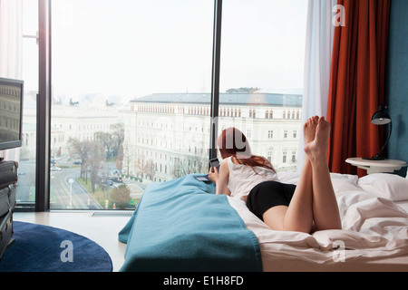 Junge Frau im Hotelzimmer mit Blick auf Straße Stockfoto