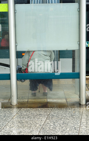 Frau sitzt am Bushäuschen. Stockfoto