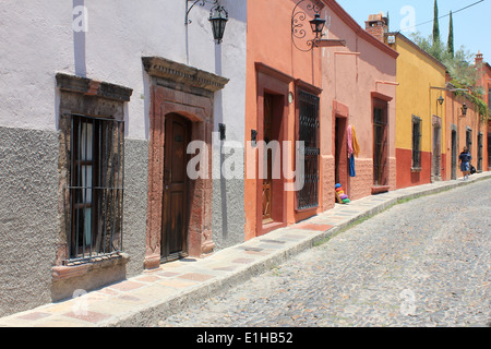 Bunte Kolonialhäuser säumen eine gepflasterte Straße in San Miguel de Allende, Guanajuato, Mexiko Stockfoto