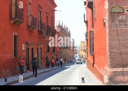 Rot und orange Kolonialbauten entlang einer gepflasterten Straße in San Miguel de Allende, Guanajuato, Mexiko Stockfoto