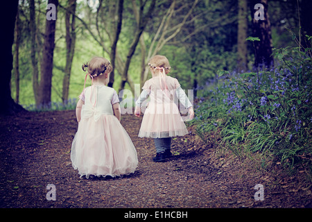 Zwei junge Kinder wandern durch einen Wald voller Glockenblumen in England. Stockfoto