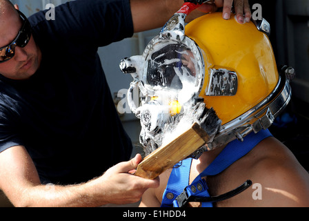 U.S. Navy Diver Gabriel Shelton, links, wäscht Taucher 2. Klasse Richard Burby KM 37 Tauchgang Helm während der Prüfung auf Dichtheit werden Stockfoto